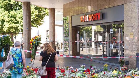 Trauerkerzen und Blumen liegen vor dem Kaufhaus, in dem der Täter Menschen mit einem Messer attackiert hatte.