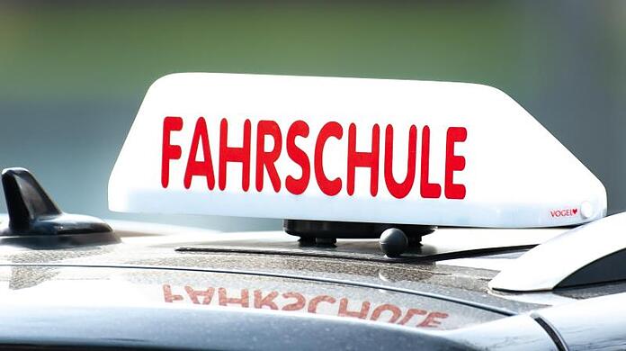 Ein Schild mit der Aufschrift "Fahrschule" ist auf einem Auto befestigt.