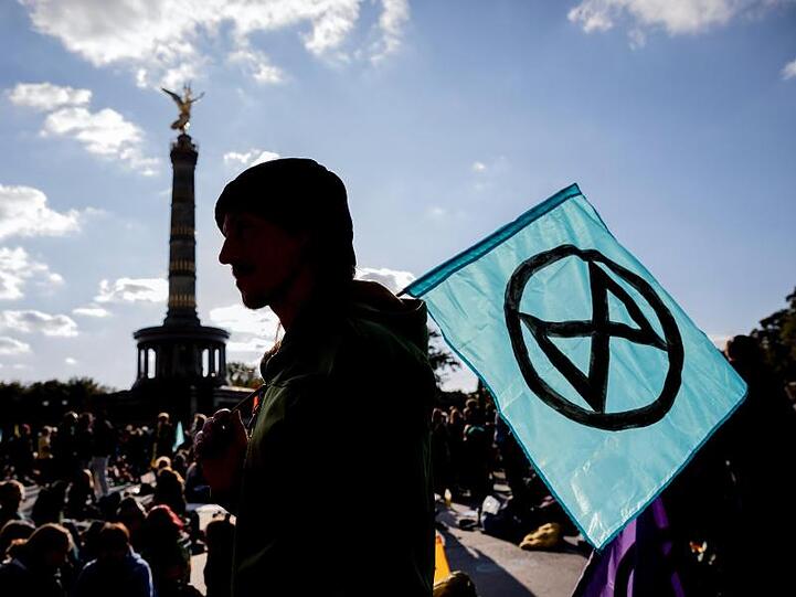 Ein Mann mit einer Extinction-Rebellion-Fahne vor der Siegessäule in Berlin.