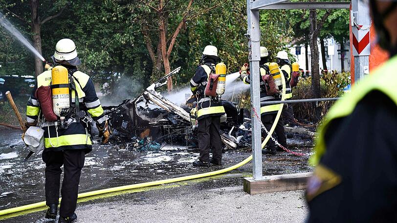 Feuerwehrkräfte mit schwerem Atemschutz löschen den Wohnwagen unter der Eisenbahnbrücke in Untergiesing.