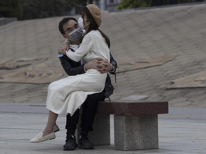Ein Paar mit Mundschutz sitzt auf einer Bank im chinesischen Wuhan. In der Stadt, in der die Corona-Pandemie begann, fallen nach elf Wochen die letzten Bewegungsbeschränkungen für die elf Millionen Bewohner.