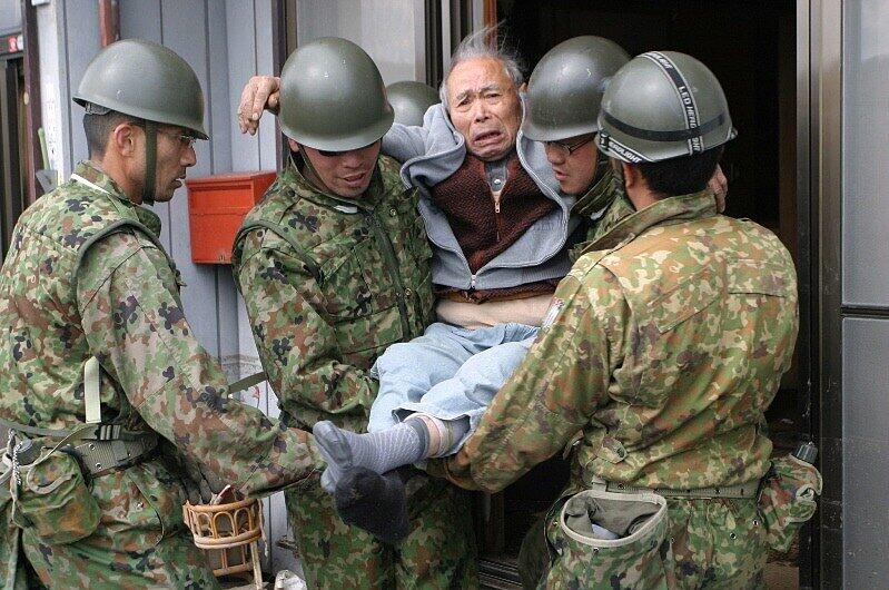 Japanische Militärs bringen einen alten Mann aus dem Katastrophengebiet
nahe Fukushima in Sicherheit.