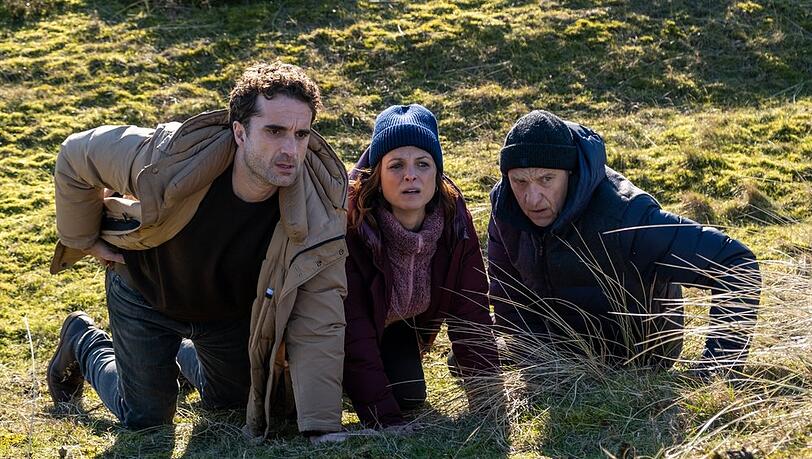 "Nord Nord Mord: Sievers und die fünf Fragezeichen": Hinnerk Feldmann (Oliver Wnuk, l.), Ina Behrendsen (Julia Brendler) und Carl Sievers (Peter Heinrich Brix) suchen Schutz hinter einem Hügel.