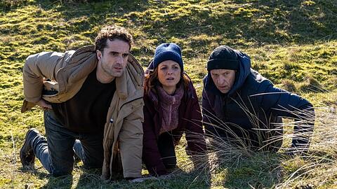 "Nord Nord Mord: Sievers und die fünf Fragezeichen": Hinnerk Feldmann (Oliver Wnuk, l.), Ina Behrendsen (Julia Brendler) und Carl Sievers (Peter Heinrich Brix) suchen Schutz hinter einem Hügel.