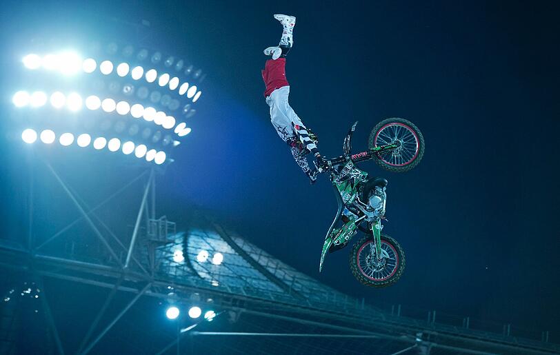 Der Freestyle-Motocross-Fahrer Eigo Sato (Japan) springt an einem Flutlichtmast und Zeltdach vorbei.