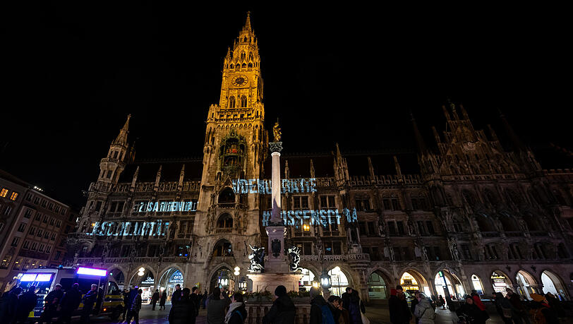 Die Wörter #Demokratie, #Zusammenhalt, #Wissenschaft, und #Solidarität werden auf die Fassade des Münchner Rathauses projiziert.