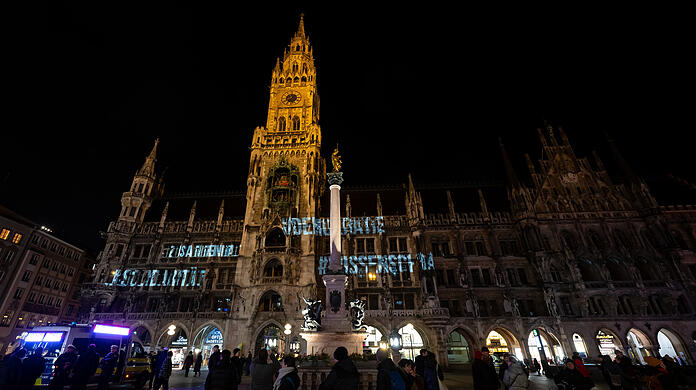 Die Wörter #Demokratie, #Zusammenhalt, #Wissenschaft, und #Solidarität werden auf die Fassade des Münchner Rathauses projiziert.