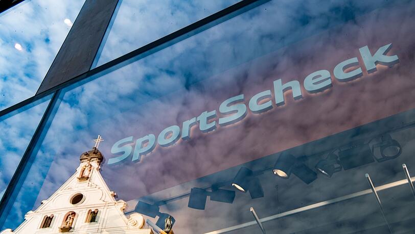 In der Fassade einer SportScheck-Filiale in der Münchener Fußgängerzone spiegelt sich ein Haus.