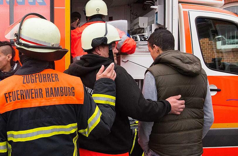 Ein Bewohner einer Flüchtlingsunterkunft wird am 14.04.2015 in Hamburg-Hammerbrook nach einem Feuer zu einem Rettungswagen gebracht.