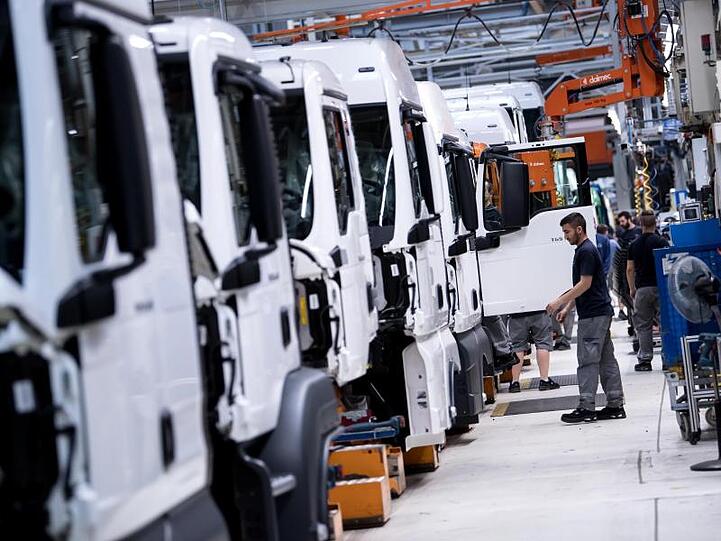 Mitarbeiter von MAN Truck & Bus arbeiten an einer Produktionsstraße an einem LKW.