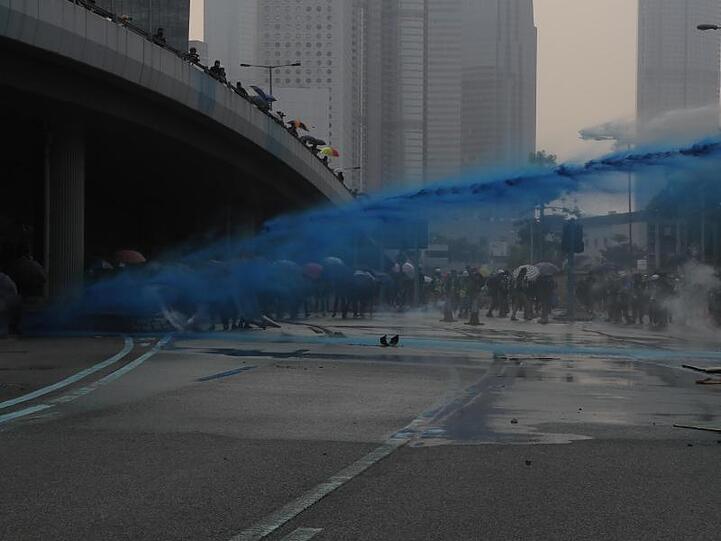 Bereitschaftspolizisten setzen in Hongkong Wasserwerfer ein, die blau eingefärbtes Wasser versprühen.