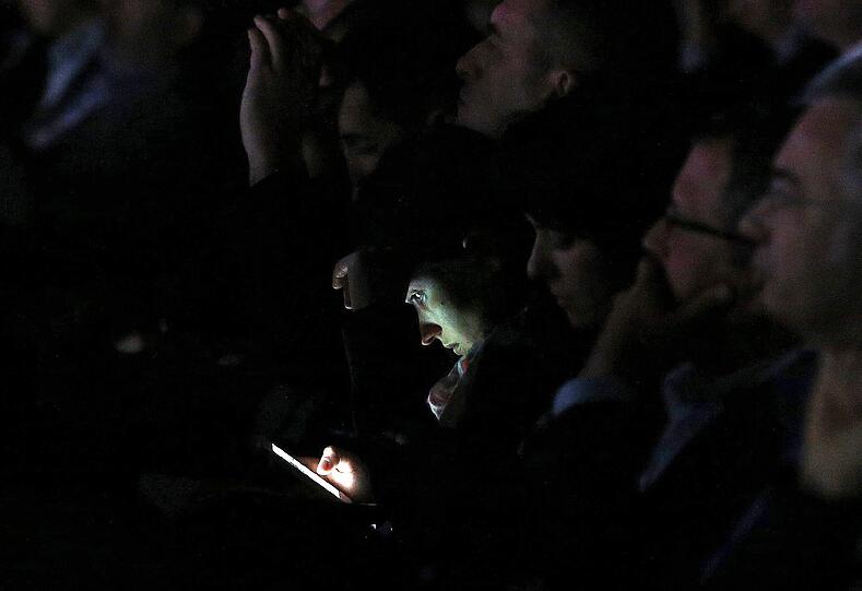 Eine Frau schaut während eines Vortrags auf ihr Smartphone. Die Bilder vom Mobile World Congress in Barcelona.
