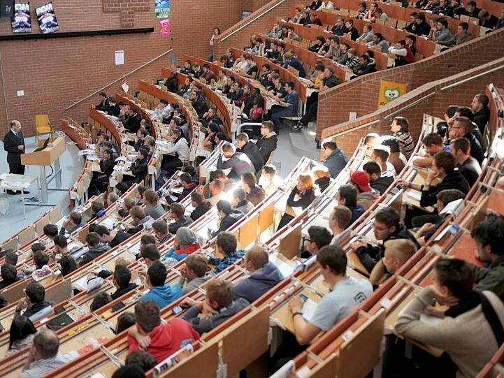Erstsemester sitzen in einem Hörsaal der Universität und nehmen an der Einführungsveranstaltung in Maschinenbau teil.