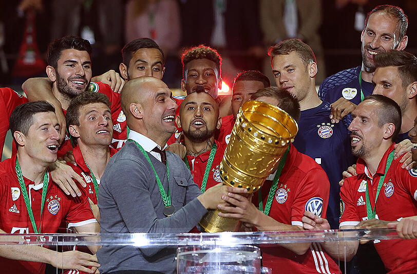 Kapitän Philipp Lahm (verdeckt) überlässt seinem scheidenden Coach Pep Guardiola (links) den Pokal zum ersten Jubler.