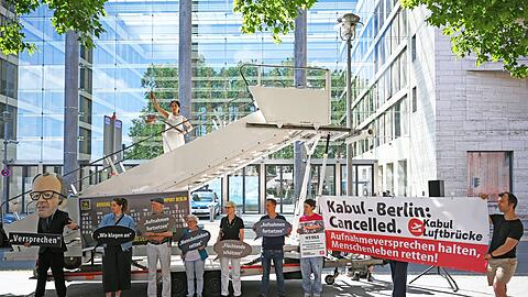Aktivsten stehen während einer symbolischen Protestaktion am Weltflüchtlingstag zur Unterstützung mehrerer Klagen von Afghanen gegen die Bundesregierung vor dem Auswärtigen Amt.
