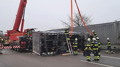 Mit Hilfe eines Autokrans wird der umgekippte Lastwagen wieder von der Feuerwehr aufgerichtet.