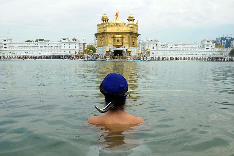 Ein Sikh-Anhänger nimmt vor dem goldenen Sikh-Schrein in Amritsar ein Bad. Anlass ist der 535. Geburtstag des Guru Amardas, dem dritten Meister der Sikh.