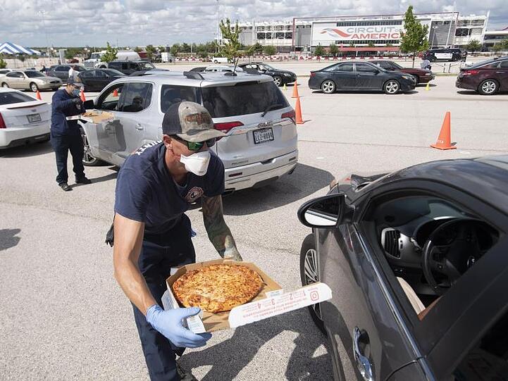 Feuerwehrleute reichen Autofahrern während der Evakuierung in Austin, Texas, Pizza.