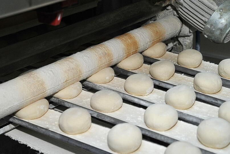 Schritt 4: Jetzt kommt echte Hand- und Bandarbeit ins Spiel: Die Bäcker formen aus dem Teig Laibe für Brote, zusätzlich Kugeln. Letztere kommen auf ein Band, das sie durch Walzen drückt &ndash; fertig ist die Semmel.