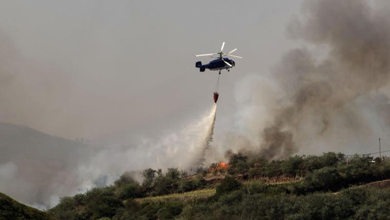Ein Löschhubschrauber im Einsatz über einem bewaldeten Hang. Ein Löschhubschrauber im Einsatz über einem bewaldeten Hang.