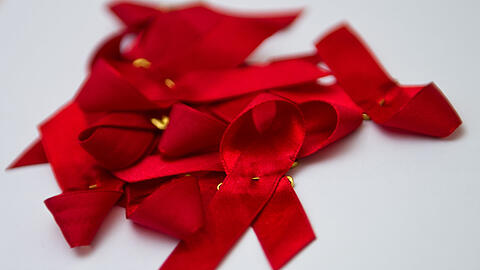 Die rote Schleife gilt weltweit als Symbol für die Solidarität mit Menschen, die sich mit HIV infiziert haben.