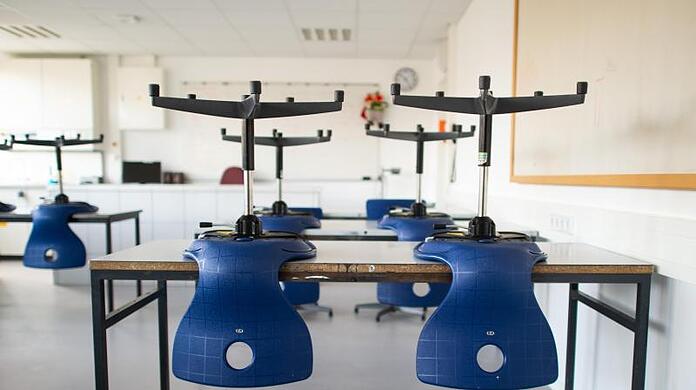 Stühle stehen in einem leeren Klassenzimmer in einem Gymnasium auf den Tischen, da der Unterricht in der Corona-Zeit ausgefallen ist.