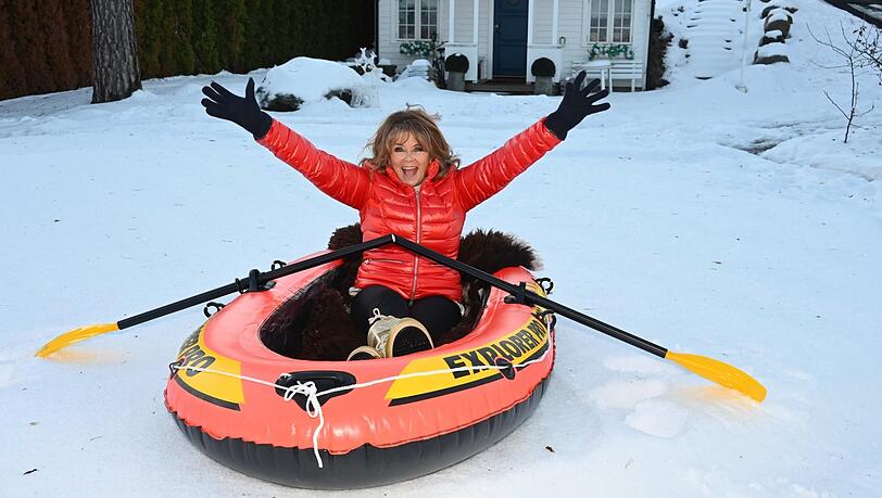 Schnee statt See: Wencke Myhre rudert fröhlich im verschneiten Garten bei Oslo im knallroten Gummiboot.