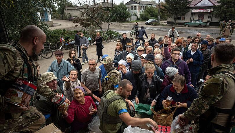 Ukrainische Soldaten verteilen Lebensmittel an an die Einwohner von Isjum.