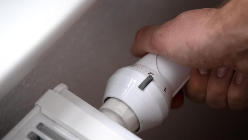 ILLUSTRATION - Ein Mann dreht am Thermostat einer Heizung. Die Großhandelspreise für Erdgas steigt und steigt.