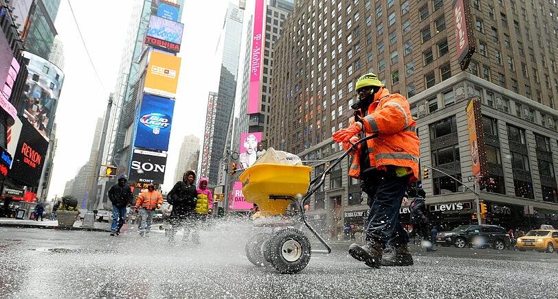 Eisiger Apfel: Ein Mitarbeiter der Stadt präpariert den Gehweg am Times Square in New York mit Streusalz. Im Januar erlebte der Big Apple einen der heftigsten Wintereinbrüche seit Jahren.