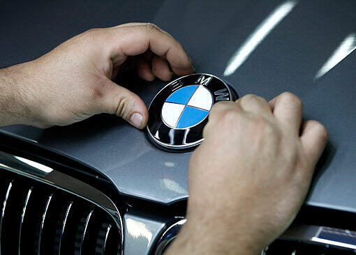 Glänzende Zahlen: Ein Arbeiter montiert im BMW-Werk in München das BMW-Logo auf die Motorhaube eines 3er BMW.