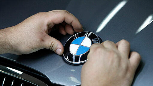 Glänzende Zahlen: Ein Arbeiter montiert im BMW-Werk in München das BMW-Logo auf die Motorhaube eines 3er BMW. Glänzende Zahlen: Ein Arbeiter montiert im BMW-Werk in München das BMW-Logo auf die Motorhaube eines 3er BMW.