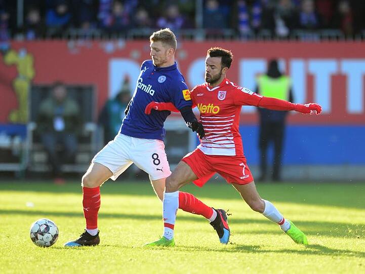 Kiels Alexander Mühling (l) und Regensburgs Albion Vrenezi kämpfen um den Ball. Foto: Daniel Bockwoldt