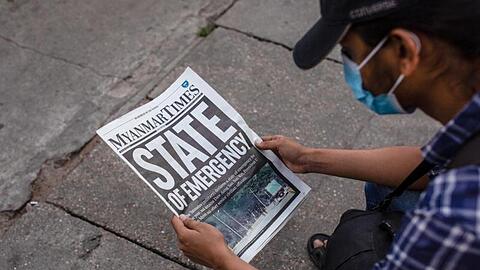 Ein Mann liest in Rangun die Zeitung "Myanmar Times" mit der Schlagzeile "Ausnahmezustand".