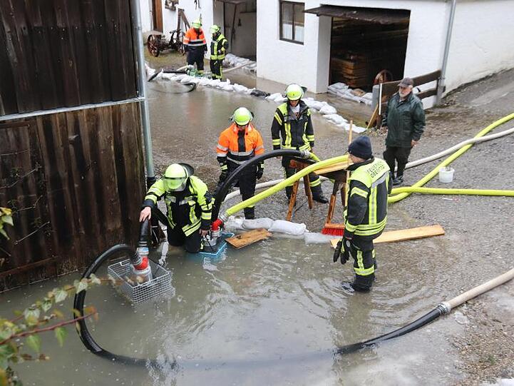 Feuerwehrleute pumpen an einem Haus bei Oberstdorf Wasser ab. Foto: Benjamin Liss/dpa