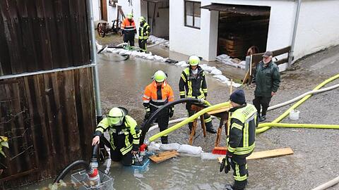 Feuerwehrleute pumpen an einem Haus bei Oberstdorf Wasser ab. Foto: Benjamin Liss/dpa