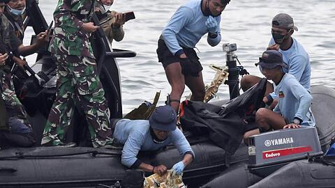 Taucher der indonesischen Marine ziehen ein Flugzeugteil aus dem Wasser.