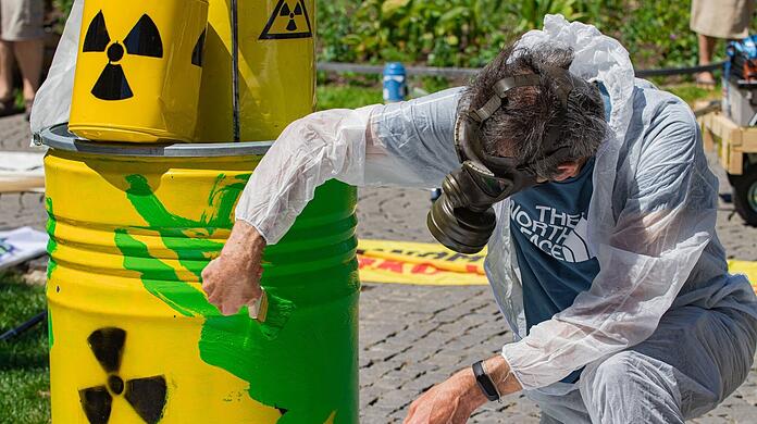 Bei einer Demo gegen die EU-Taxonomie Ende Mai in München malt ein Demonstrant ein symbolisches Atommüllfass grün an.