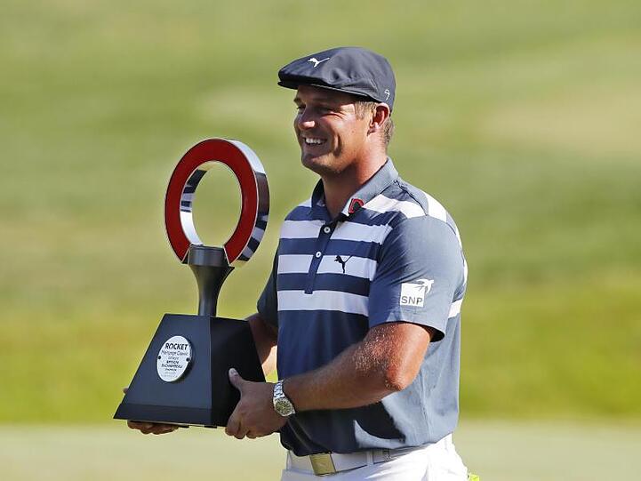 Bryson DeChambeau hält die Trophäe des Golfturniers Rocket Mortgage Classic in den Händen.