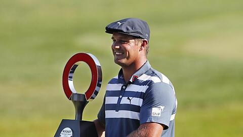 Bryson DeChambeau hält die Trophäe des Golfturniers Rocket Mortgage Classic in den Händen.