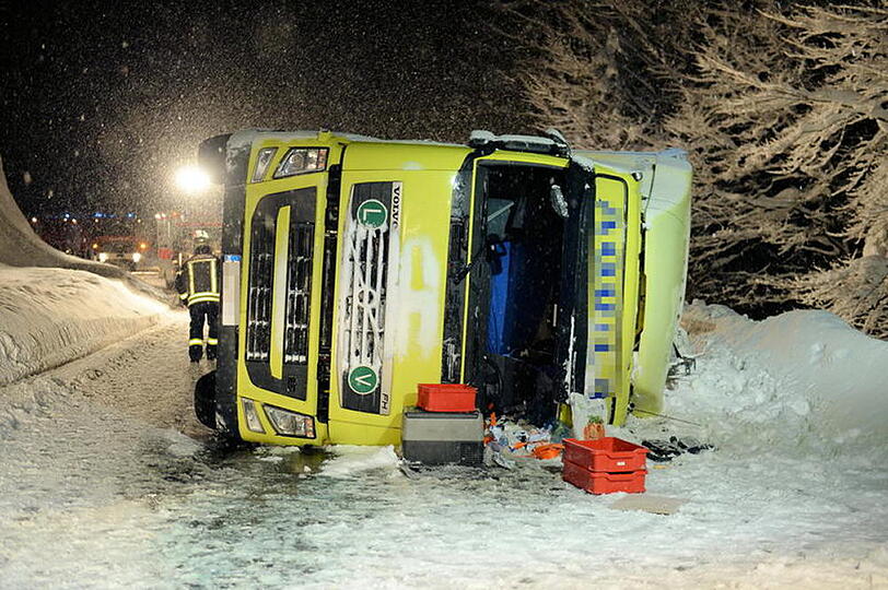 Ein LKW kommt auf schneeglatter Fahrbahn ins Rutschen und kippt um
