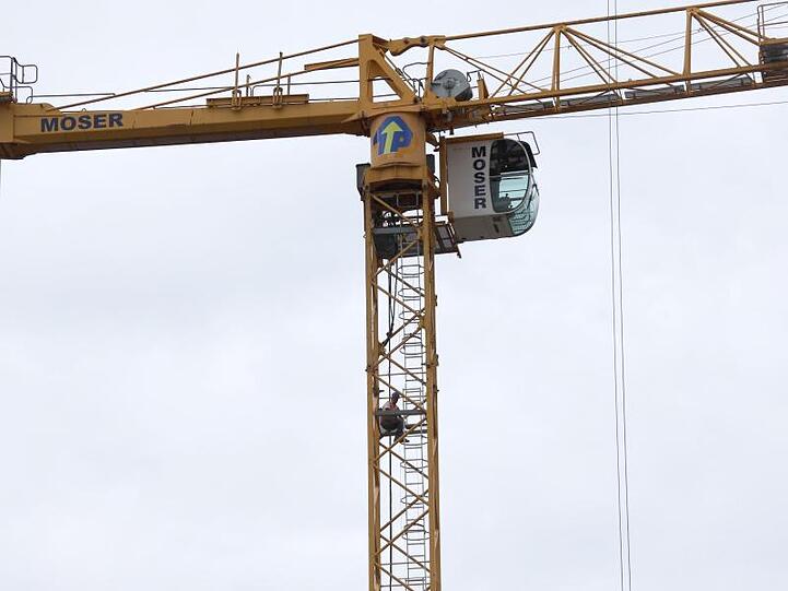 Ein Bauarbeiter sitzt auf einem Baukran. Foto: Alexander Auer/dpa