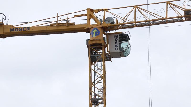 Ein Bauarbeiter sitzt auf einem Baukran. Foto: Alexander Auer/dpa