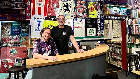 Seit 20 Jahren gibt es das Stadion an der Schleißheimer Straße. An den Wänden hängen viele Trikots und Schals – von Fans gespendet. Im "Stadion" seien Anhänger aller Vereine willkommen, sagen die Betreiber Holger "Holle" Britzius (l.) und Michael "Michel" Jachan.