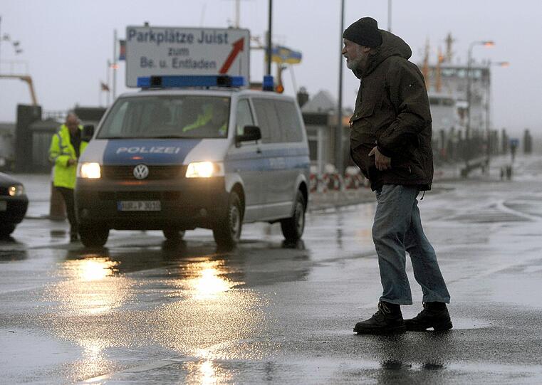 Ein Mann überquert bei schweren Sturmböen die von der Polizei gesperrte Zufahrtstraße zum Fährhafen von Norden-Norddeich (Niedersachsen).