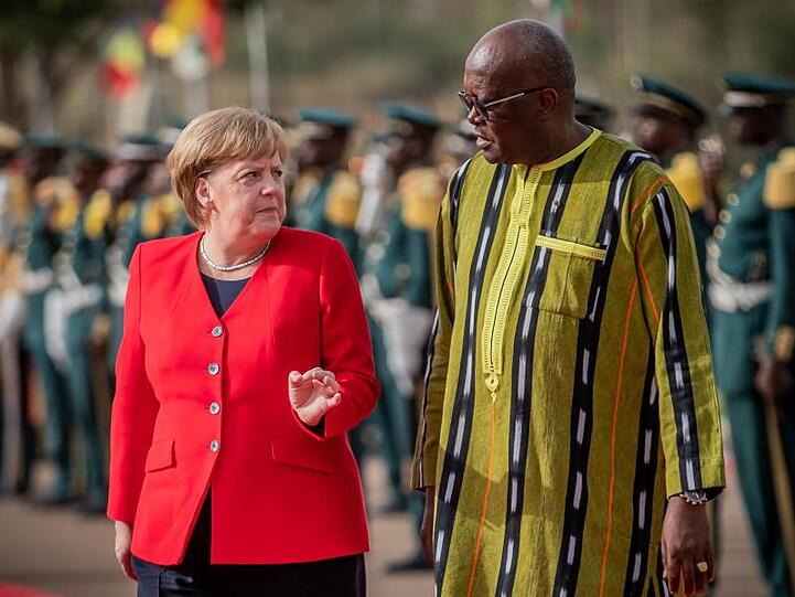 Bundeskanzlerin Angela Merkel wird mit militärischen Ehren von Burkina Fasos Staatschef Roch Marc Kaboré am Präsidentenpalast begrüßt.