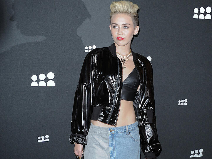 Miley Cyrus stylt ein Lack-Blouson zum Crop Top