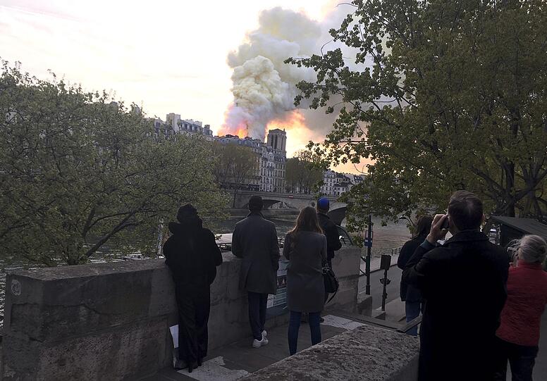 Die weltberühmte Kathedrale Notre-Dame de Paris steht in Flammen. Schaulustige haben sich versammelt.