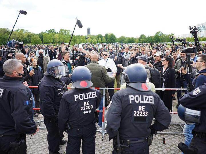 Durch eine Absperrung getrennt stehen Polizeibeamte vor dem Reichstag einer größeren Zahl von Demonstranten gegenüber.