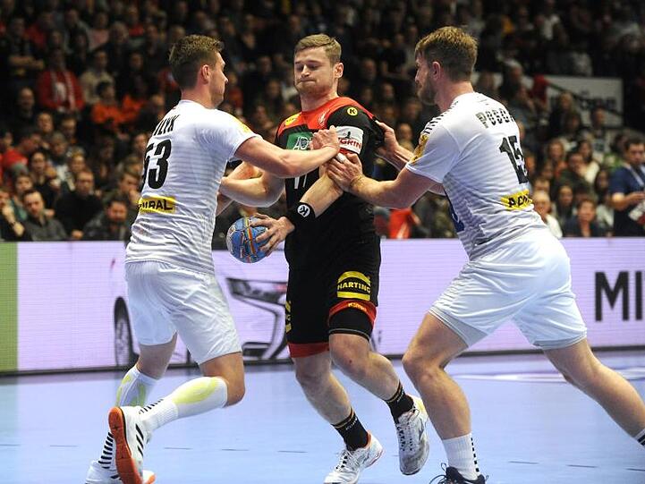 Die Österreicher Nikola Bilyk (l) und Fabian Posch (r) versuchen am Wurfkreis DHB-Spieler David Schmidt aufzuhalten.